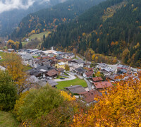 Blick auf Viehhofen im herbstlichen Glemmtal mit Häusern im Ortszentrum, bunt gefärbten Bäumen und bewaldeten Berghängen. | © viehhofen.at, Der Fotoigel