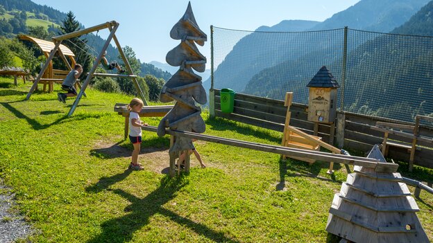 Kinder spielen an einer großen hölzernen Kugelbahn in Viehhofen mit verschiedenen Spielelementen und Schaukel vor der Bergkulisse. | © viehhofen.at, Der Fotoigel