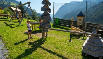 Children playing at a large wooden marble run in Viehhofen with various play elements and a swing against a mountain backdrop. | © viehhofen.at, Der Fotoigel