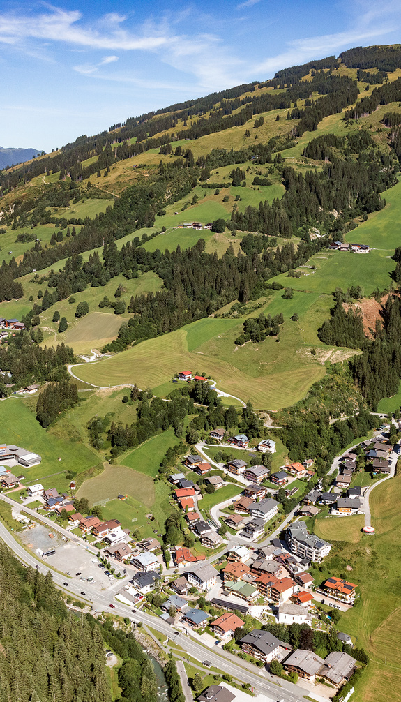 Aerial view of Viehhofen in summer, showing the village in the valley, green meadows, forested mountain slopes and the surrounding landscape of the Glemmtal valley. | © viehhofen.at, Amido