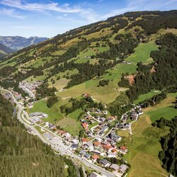 Luchtfoto van Viehhofen in de zomer met het dorp in het dal, groene weiden, beboste berghellingen en het omliggende landschap van het Glemmtal. | © viehhofen.at, Amido