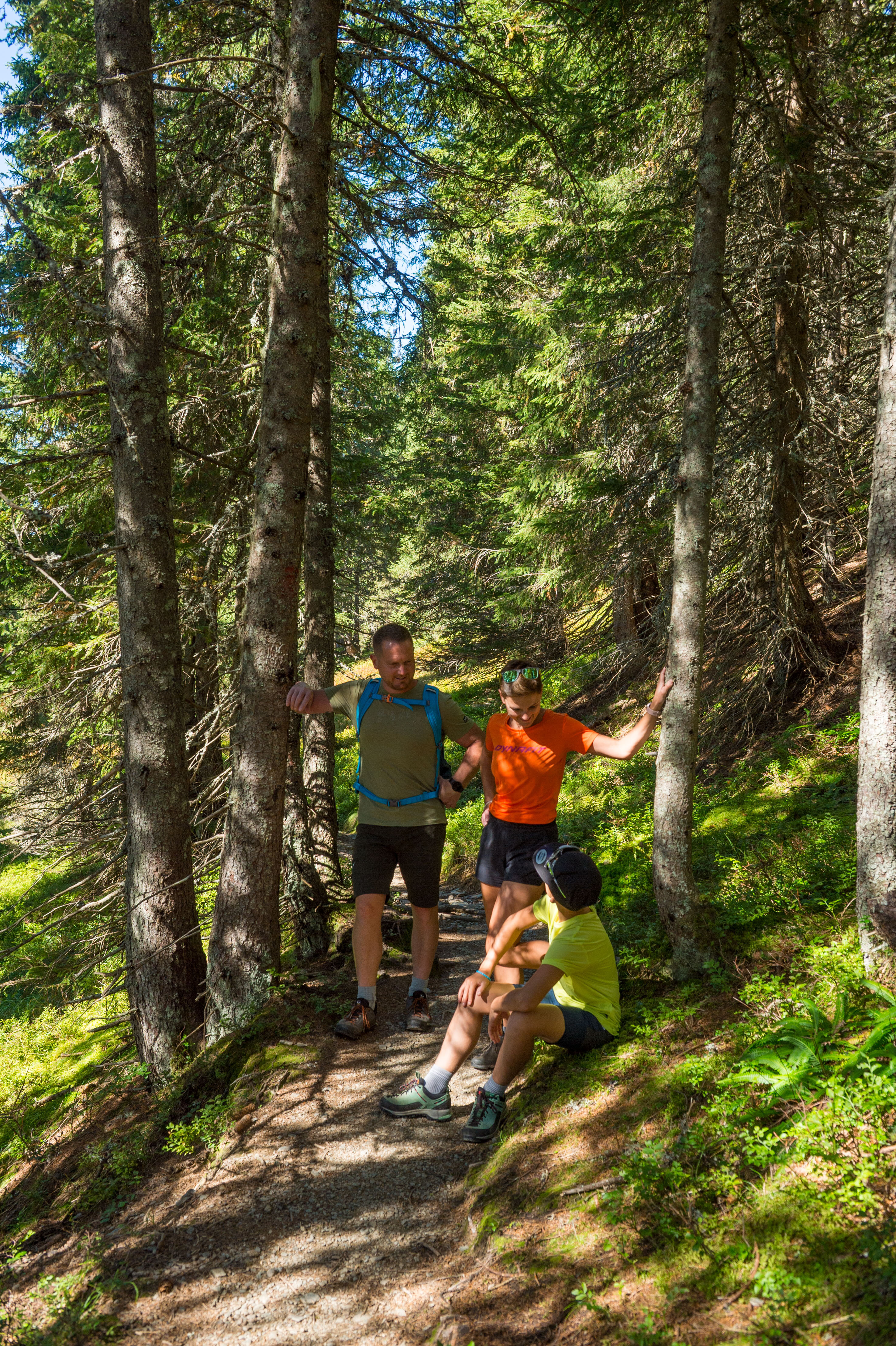 Familie beim Wandern in Viehhofen auf einem schmalen Waldweg, während ein Kind eine kurze Pause macht und die Erwachsenen daneben stehen. | © viehhofen.at, Der Fotoigel