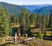 Group of hikers taking a break beside a small natural pond in Viehhofen, surrounded by forest with wide views of the surrounding mountains. | © viehhofen.at, Der Fotoigel