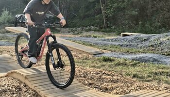 Child riding a mountain bike over a wave-shaped wooden obstacle at the Bike Skills Park in Viehhofen. | © viehhofen.at