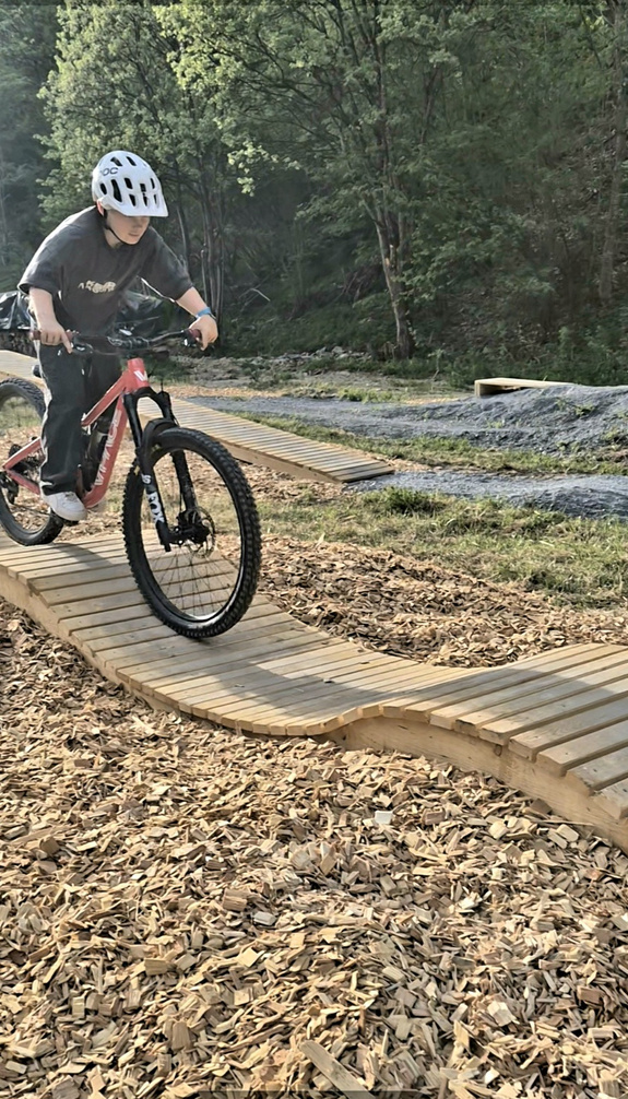 Kind fährt mit einem Mountainbike über ein wellenförmiges Holzhindernis im Bike Skills Park in Viehhofen. | © viehhofen.at