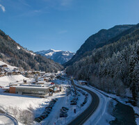 Winterlicher Blick auf Viehhofen mit zellamseeXpress, verschneitem Tal, Häusern, Bergstraße und bewaldeten Berghängen im Glemmtal. | © viehhofen.at, Der Fotoigel