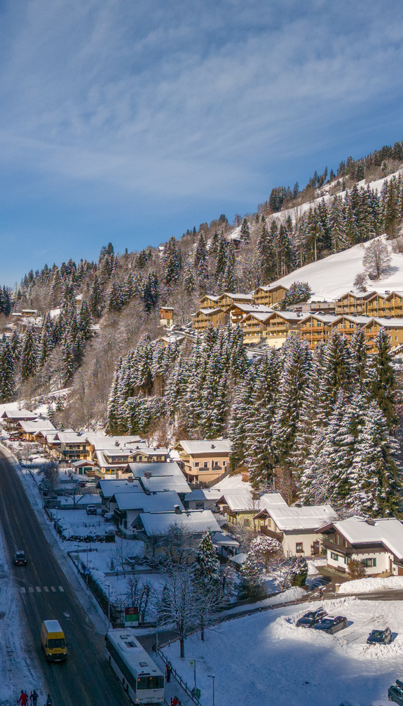Winterlicher Blick auf Viehhofen mit verschneiten Häusern, Unterkünften, Talstraße und schneebedeckten Berghängen. | © viehhofen.at, Der Fotoigel