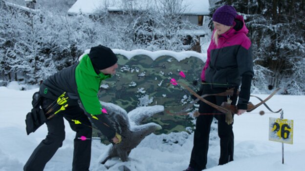 Two people practising archery on the winter archery course in Viehhofen beside a 3D animal target in deep snow. | © Der Fotoigel