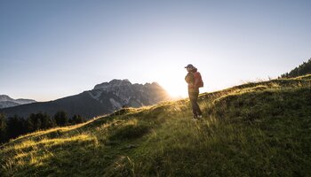 Frau mit Rucksack wandert am Saalachtaler Höhenweg. Die Sonne geht unter. | © SalzburgerLand Tourismus