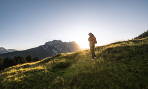 Frau mit Rucksack wandert am Saalachtaler Höhenweg. Die Sonne geht unter. | © SalzburgerLand Tourismus